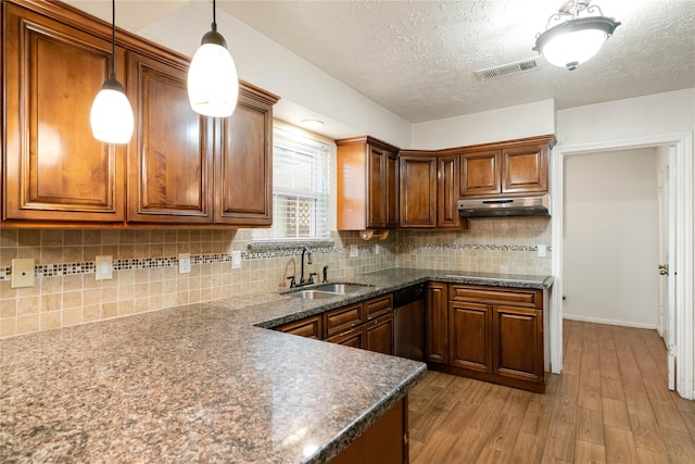 kitchen with a sink, dishwasher, light wood-type flooring, under cabinet range hood, and visible vents