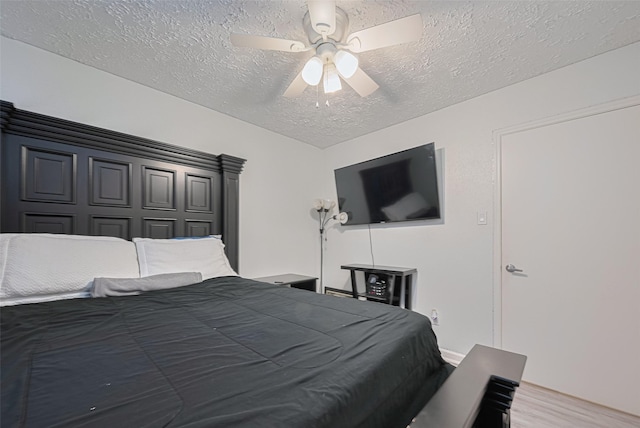 bedroom with ceiling fan, light wood-type flooring, and a textured ceiling