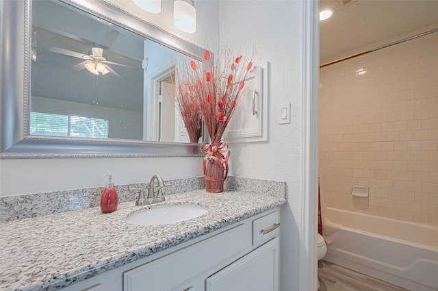 bathroom featuring vanity, a textured wall, toilet, ceiling fan, and shower / bath combo