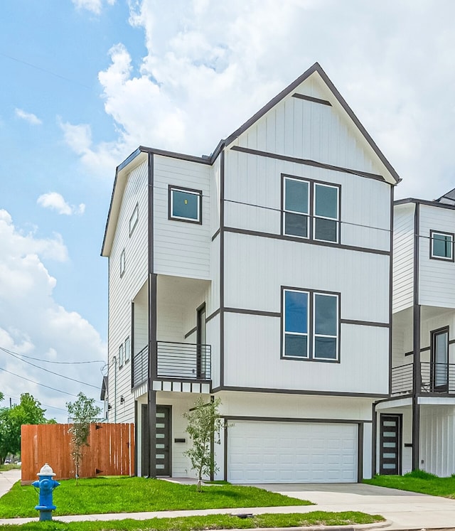 3114 Orange St, Houston, TX 77020 - contemporary house featuring a front lawn, fence, a balcony, concrete driveway, and an attached garage