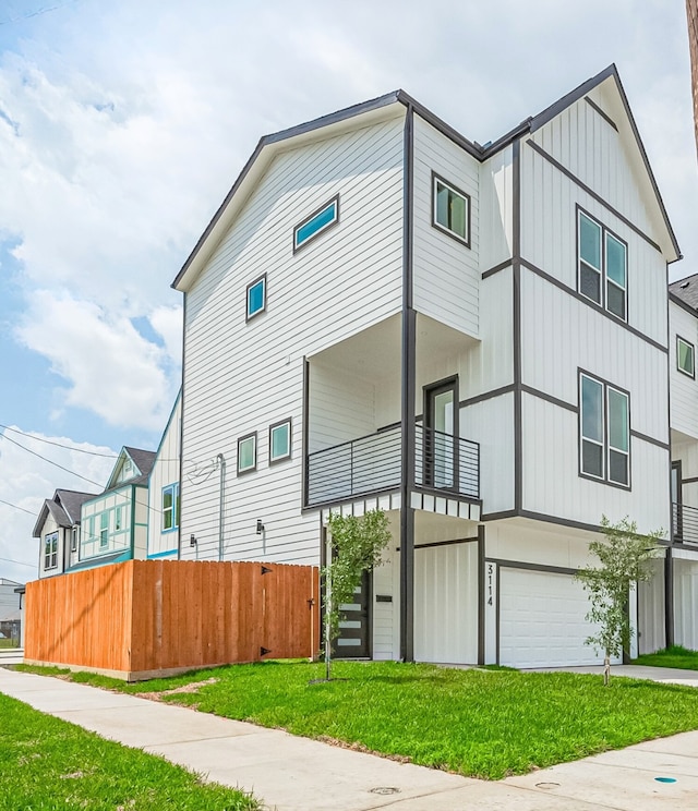 3114 Orange St, Houston, TX 77020 - view of front of property featuring a front lawn, fence, a balcony, board and batten siding, and an attached garage