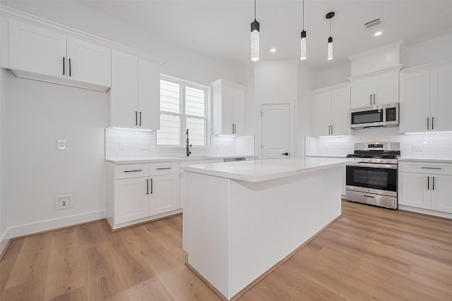 3114 Orange St, Houston, TX 77020 - kitchen featuring light wood-style floors, backsplash, stainless steel appliances, and white cabinetry