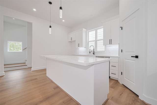 3114 Orange St, Houston, TX 77020 - kitchen with decorative backsplash, a kitchen island, recessed lighting, white cabinetry, and light wood-style flooring