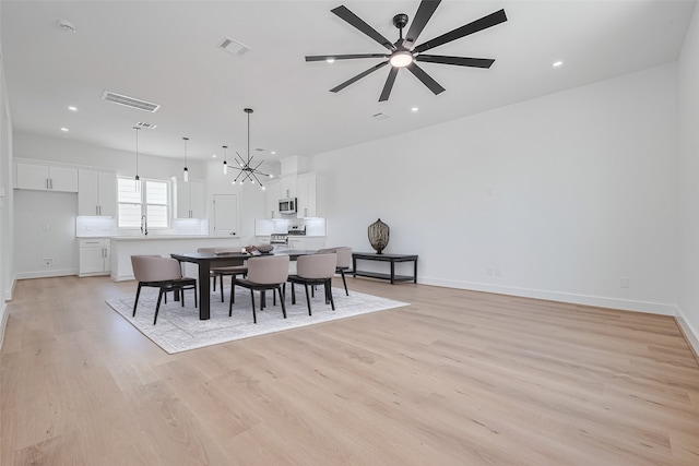 3114 Orange St, Houston, TX 77020 - dining space featuring visible vents, light wood finished floors, and ceiling fan with notable chandelier