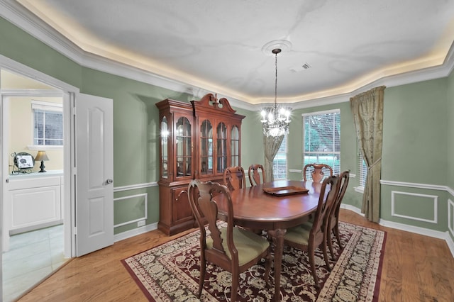 13262 Royal Rdg, Conroe, TX 77302 - dining space featuring a raised ceiling, a chandelier, light wood-style floors, crown molding, and a decorative wall