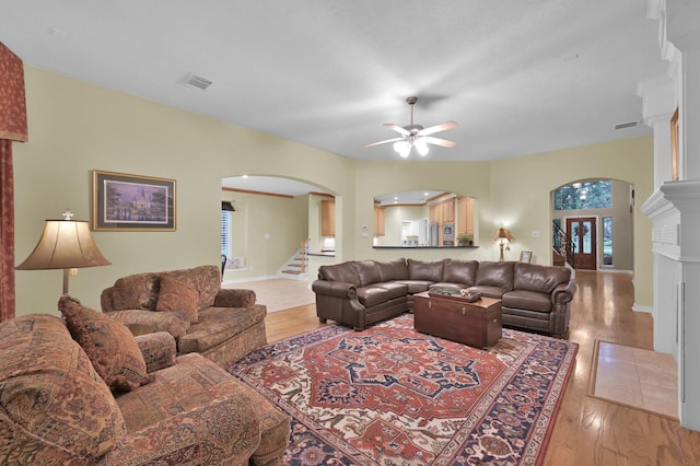 13262 Royal Rdg, Conroe, TX 77302 - living area featuring arched walkways, a ceiling fan, light wood-type flooring, stairs, and baseboards
