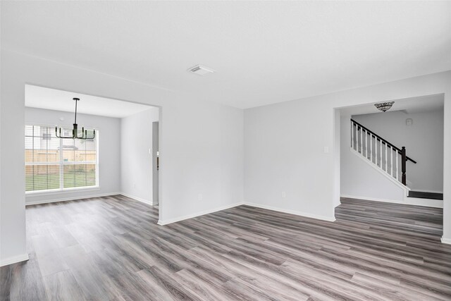 4523 Natural Bridge Dr, Kingwood, TX 77345 - unfurnished living room featuring wood finished floors, a chandelier, baseboards, and stairway