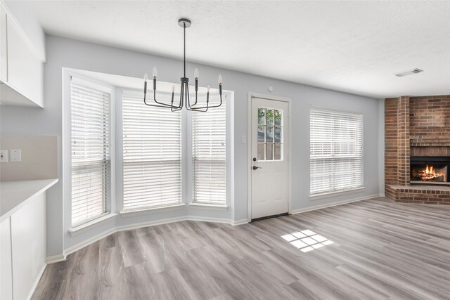 4523 Natural Bridge Dr, Kingwood, TX 77345 - unfurnished dining area with a chandelier, wood finished floors, baseboards, and a fireplace