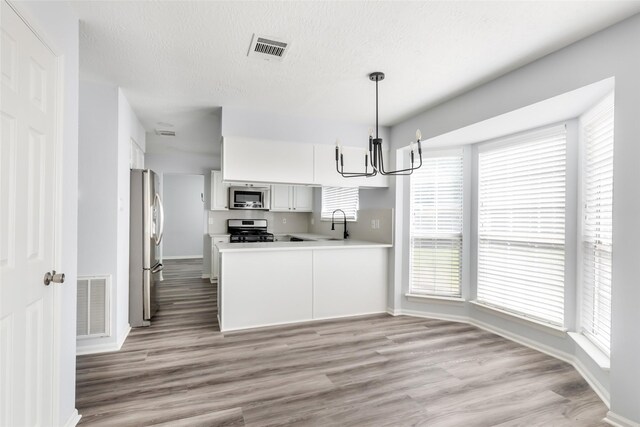 4523 Natural Bridge Dr, Kingwood, TX 77345 - kitchen featuring stainless steel appliances, a chandelier, baseboards, and light wood finished floors