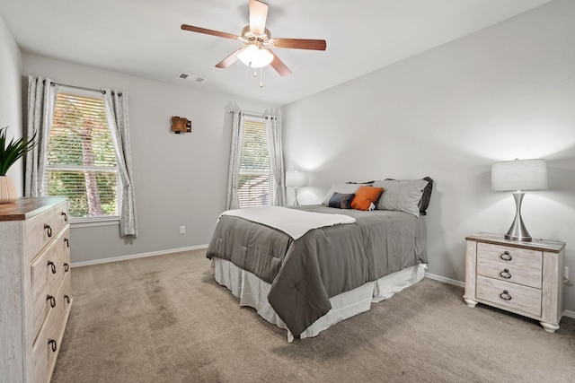 bedroom featuring light colored carpet, baseboards, visible vents, and a ceiling fan
