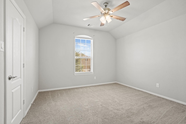 carpeted empty room with a ceiling fan, baseboards, visible vents, and vaulted ceiling