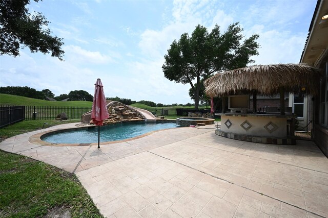 12107 Canyon Mills Dr, Houston, TX 77095 - view of pool featuring a water slide, a patio, a fenced backyard, and a pool with connected hot tub