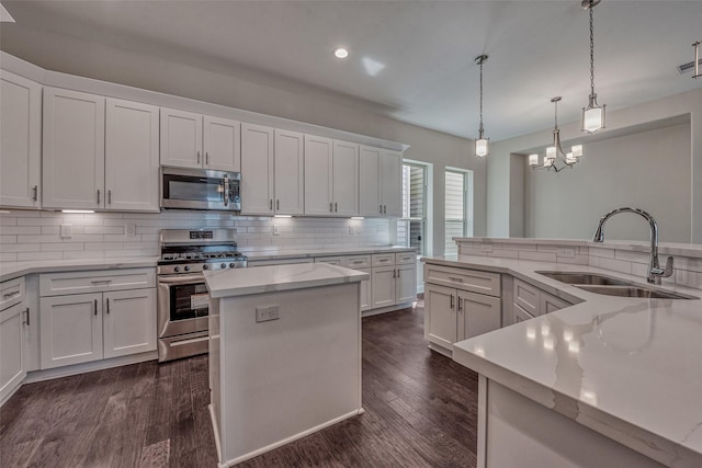 kitchen with decorative backsplash, a spacious island, white cabinetry, a sink, and stainless steel appliances