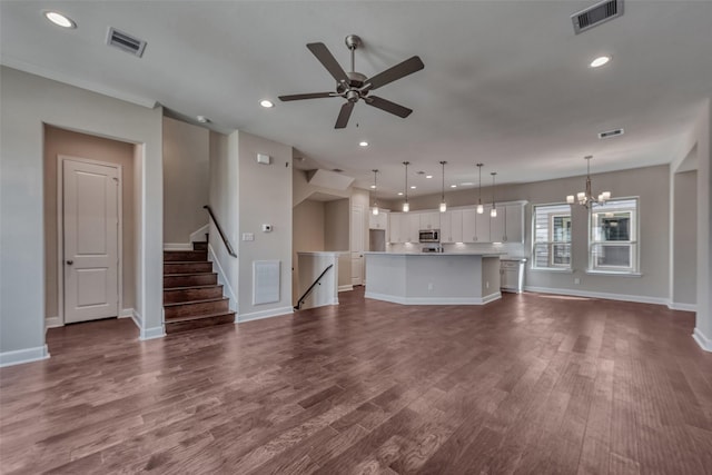 unfurnished living room with baseboards, ceiling fan with notable chandelier, and visible vents