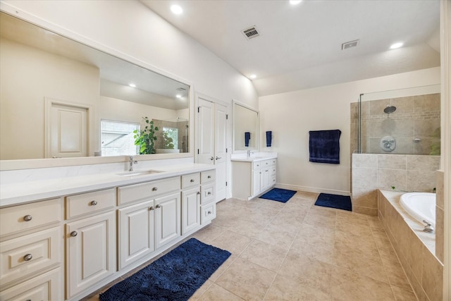 full bath with visible vents, walk in shower, two vanities, a sink, and vaulted ceiling