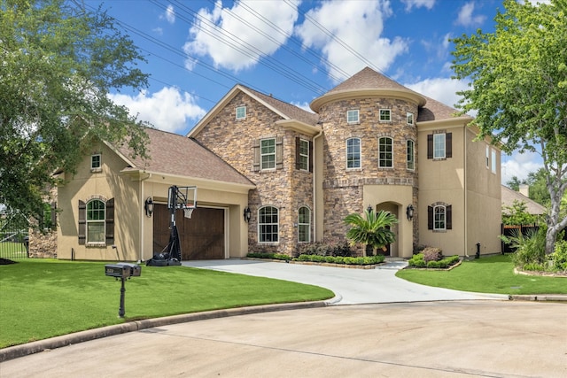 french country home with fence, a front lawn, concrete driveway, stone siding, and stucco siding