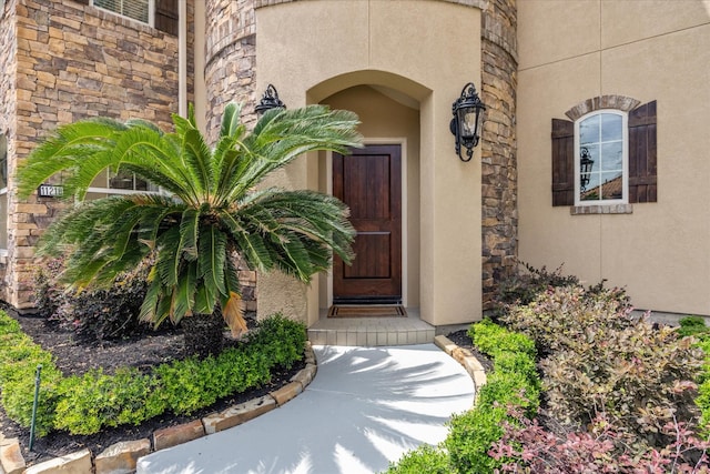 doorway to property featuring stone siding and stucco siding