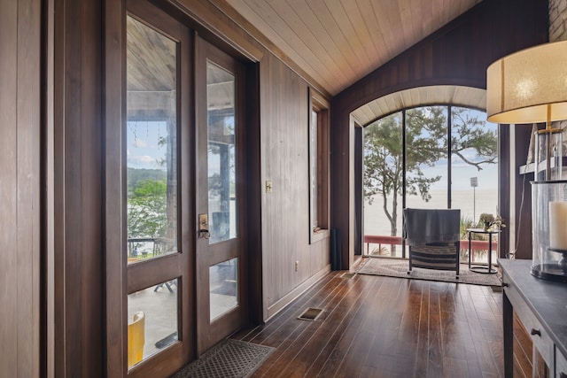 entryway featuring wooden walls, dark wood-style floors, and vaulted ceiling