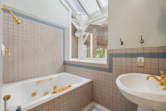 bathroom featuring a whirlpool tub, tile patterned floors, tile walls, and a sink