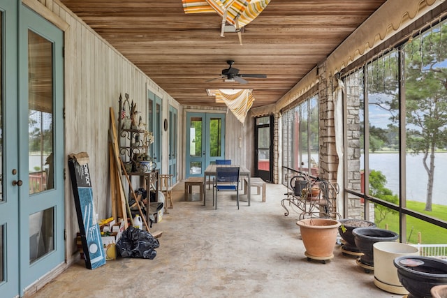 sunroom / solarium with a water view, a ceiling fan, and french doors