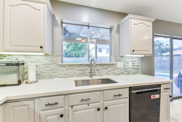 kitchen with white cabinets, a sink, light countertops, tasteful backsplash, and stainless steel dishwasher