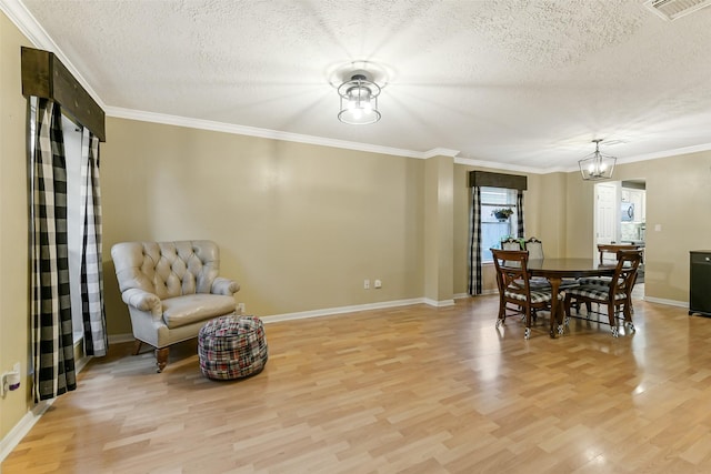 dining area with light wood-style floors, baseboards, a textured ceiling, and visible vents