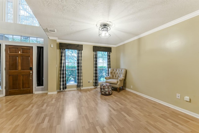 unfurnished room with visible vents, ornamental molding, baseboards, a textured ceiling, and light wood-style flooring