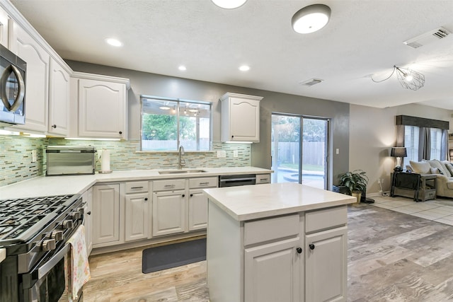 kitchen with backsplash, gas stove, visible vents, and a sink