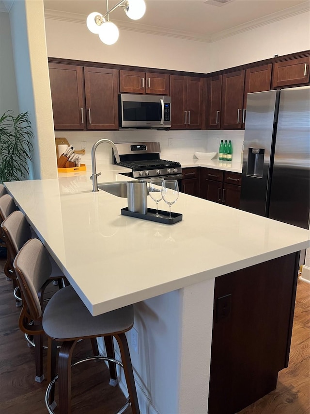 4327 Robertson St, Houston, TX 77009 - kitchen featuring crown molding, a breakfast bar area, dark brown cabinetry, and stainless steel appliances