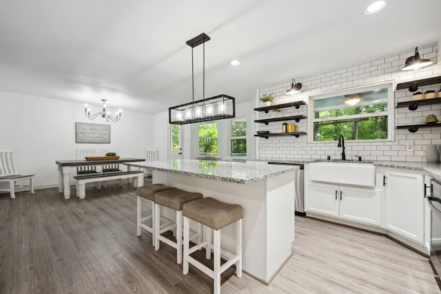 kitchen with a sink, decorative backsplash, open shelves, and dishwasher