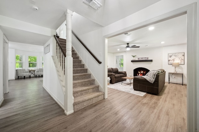 stairs with visible vents, ceiling fan, wood finished floors, and a fireplace