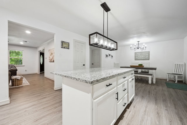 kitchen featuring light wood-style floors, a center island, white cabinets, and a notable chandelier