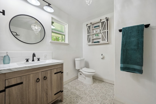 bathroom featuring toilet, baseboards, and vanity