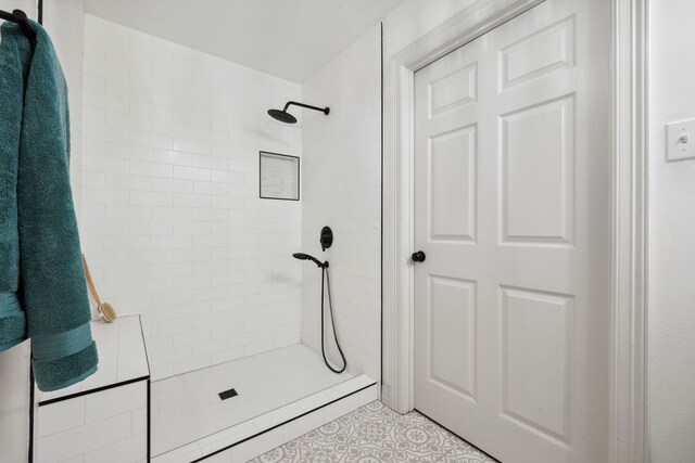 bathroom featuring tile patterned flooring and a tile shower