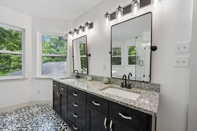 full bath featuring a sink, baseboards, a stall shower, and double vanity