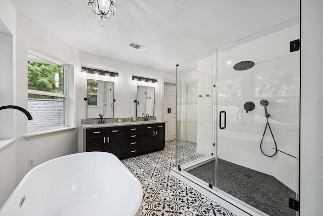 full bathroom with a sink, double vanity, a freestanding tub, visible vents, and a stall shower
