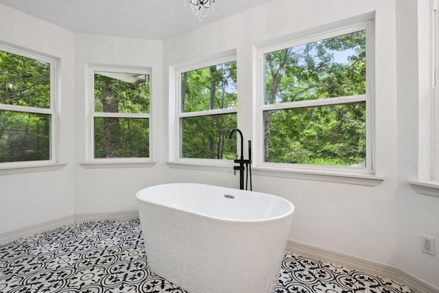 bathroom with baseboards, a freestanding bath, and an inviting chandelier