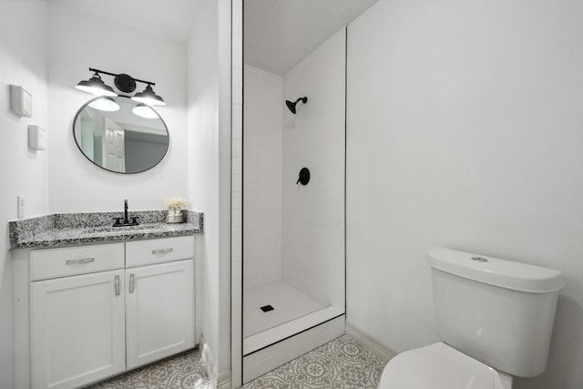 bathroom featuring vanity, toilet, baseboards, tile patterned floors, and a tile shower