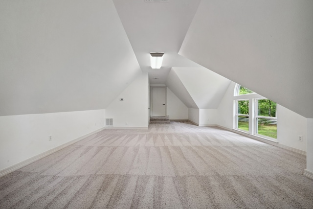 additional living space with visible vents, baseboards, vaulted ceiling, and light carpet