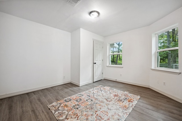unfurnished room featuring a healthy amount of sunlight, baseboards, wood finished floors, and visible vents
