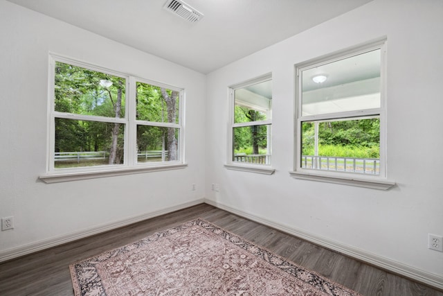 spare room with baseboards, wood finished floors, and visible vents