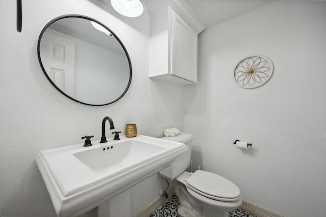 half bathroom with toilet, baseboards, and a sink