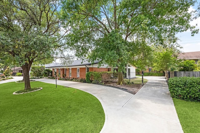 view of front of home featuring fence, a gate, brick siding, and a front yard