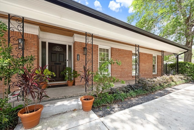 property entrance featuring brick siding and covered porch