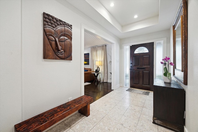 entrance foyer featuring baseboards, recessed lighting, and a raised ceiling