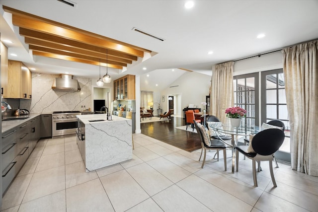 kitchen featuring a kitchen island with sink, high end stainless steel range oven, tasteful backsplash, recessed lighting, and wall chimney exhaust hood