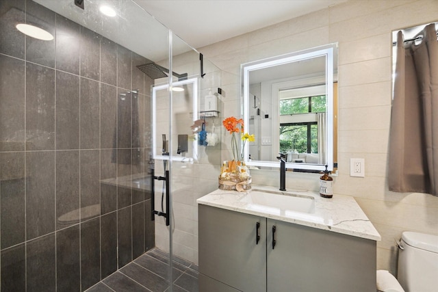 bathroom featuring vanity, a stall shower, toilet, and tile walls