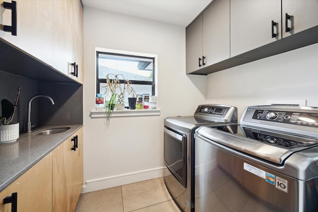 clothes washing area with independent washer and dryer, cabinet space, a sink, light tile patterned floors, and baseboards