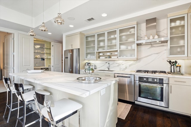 2207 Bancroft St Unit 301, Houston, TX 77027 - kitchen with stainless steel appliances, wall chimney exhaust hood, a breakfast bar, recessed lighting, and hanging light fixtures