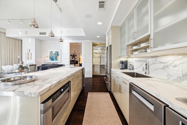 2207 Bancroft St Unit 301, Houston, TX 77027 - kitchen featuring appliances with stainless steel finishes, a sink, dark wood-type flooring, light stone countertops, and hanging light fixtures